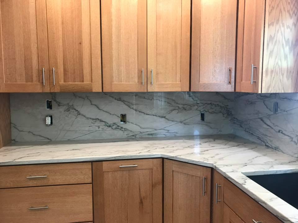 Kitchen with light wood cabinets, white marble countertops, and a matching backsplash.