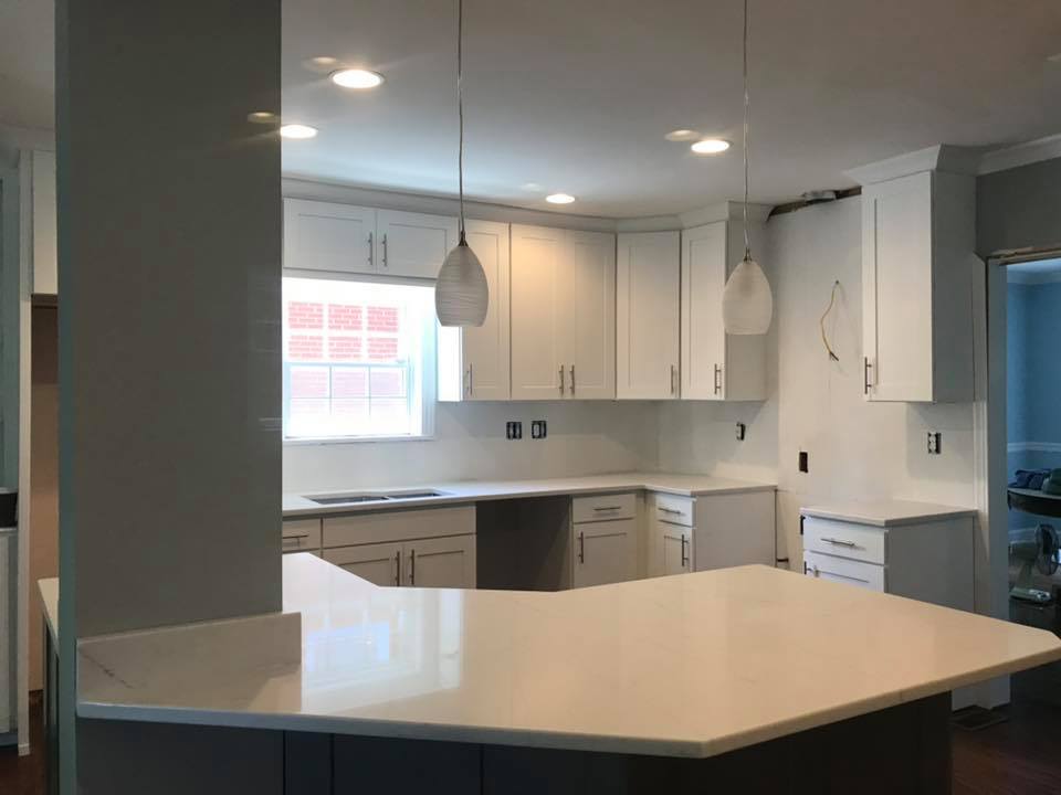 Modern kitchen with white cabinets, quartz countertops, and hanging pendant lights.