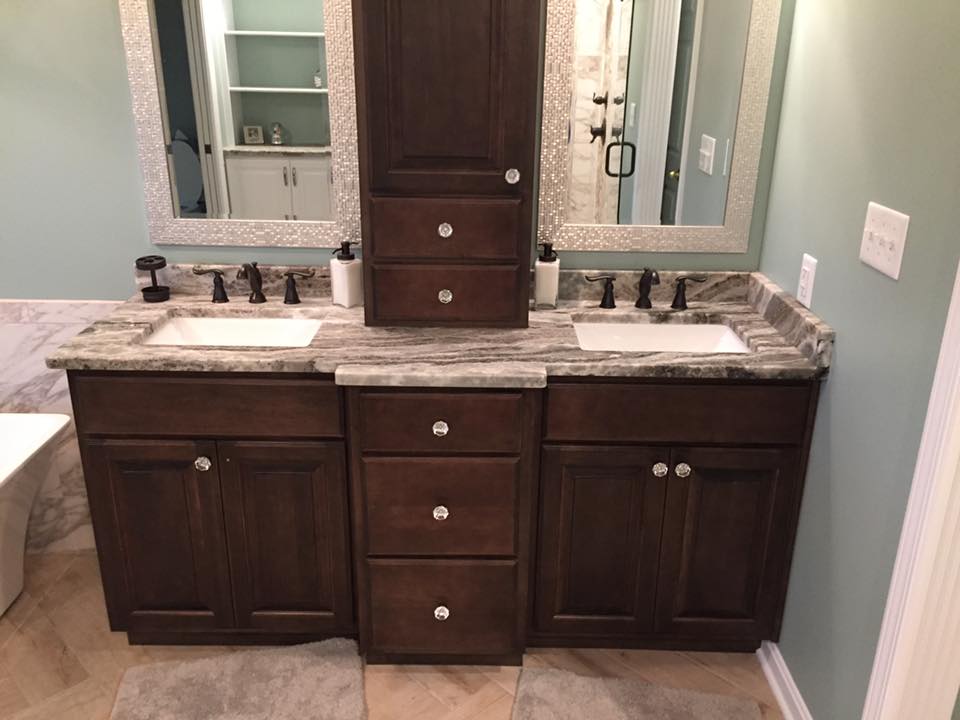 Dark wood bathroom vanity with two sinks, a central cabinet, and two mirrors. Light blue walls.