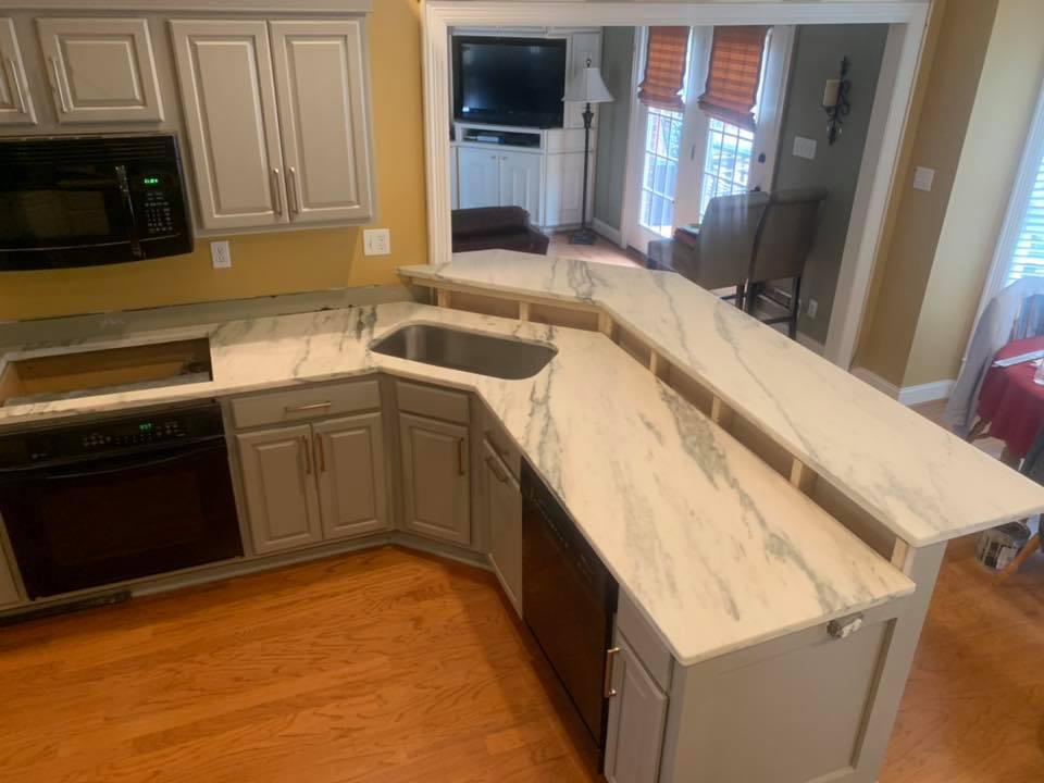 Kitchen with gray cabinets, marble countertops, sink, and an island.