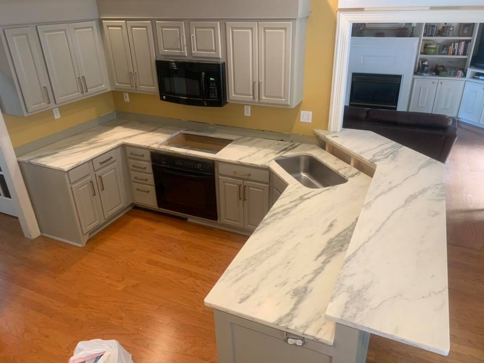 U-shaped kitchen with gray cabinets, white marble countertops, stainless steel sink, and a bar area.