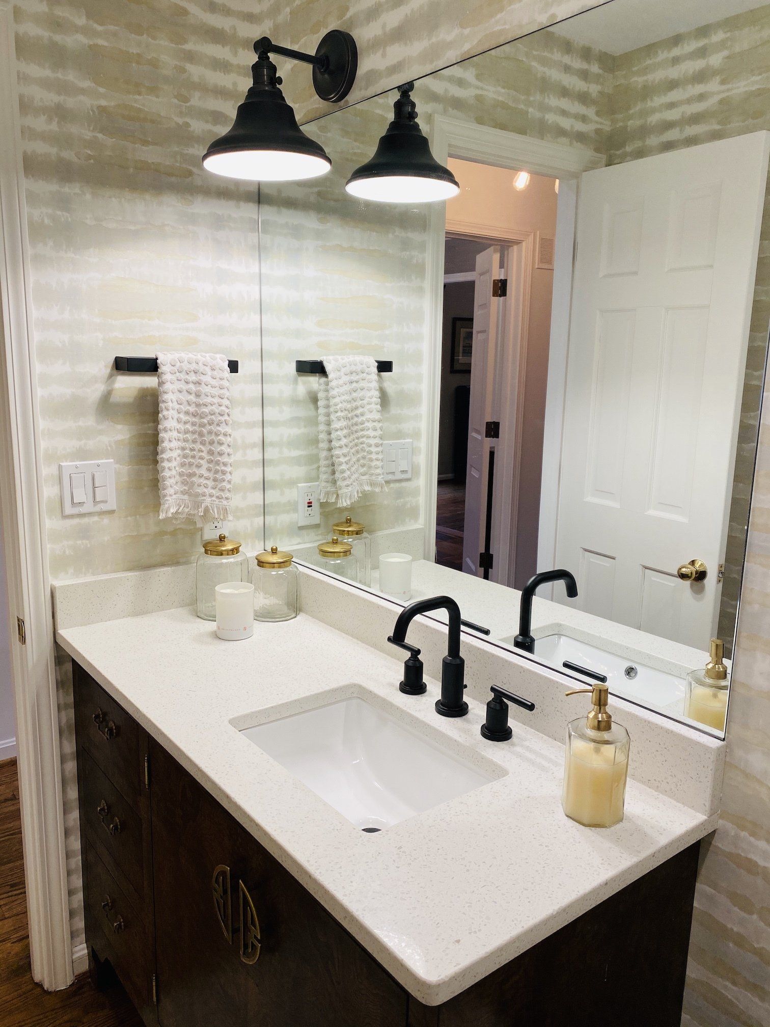 Modern bathroom vanity with black fixtures, large mirror, and white countertop and sink
