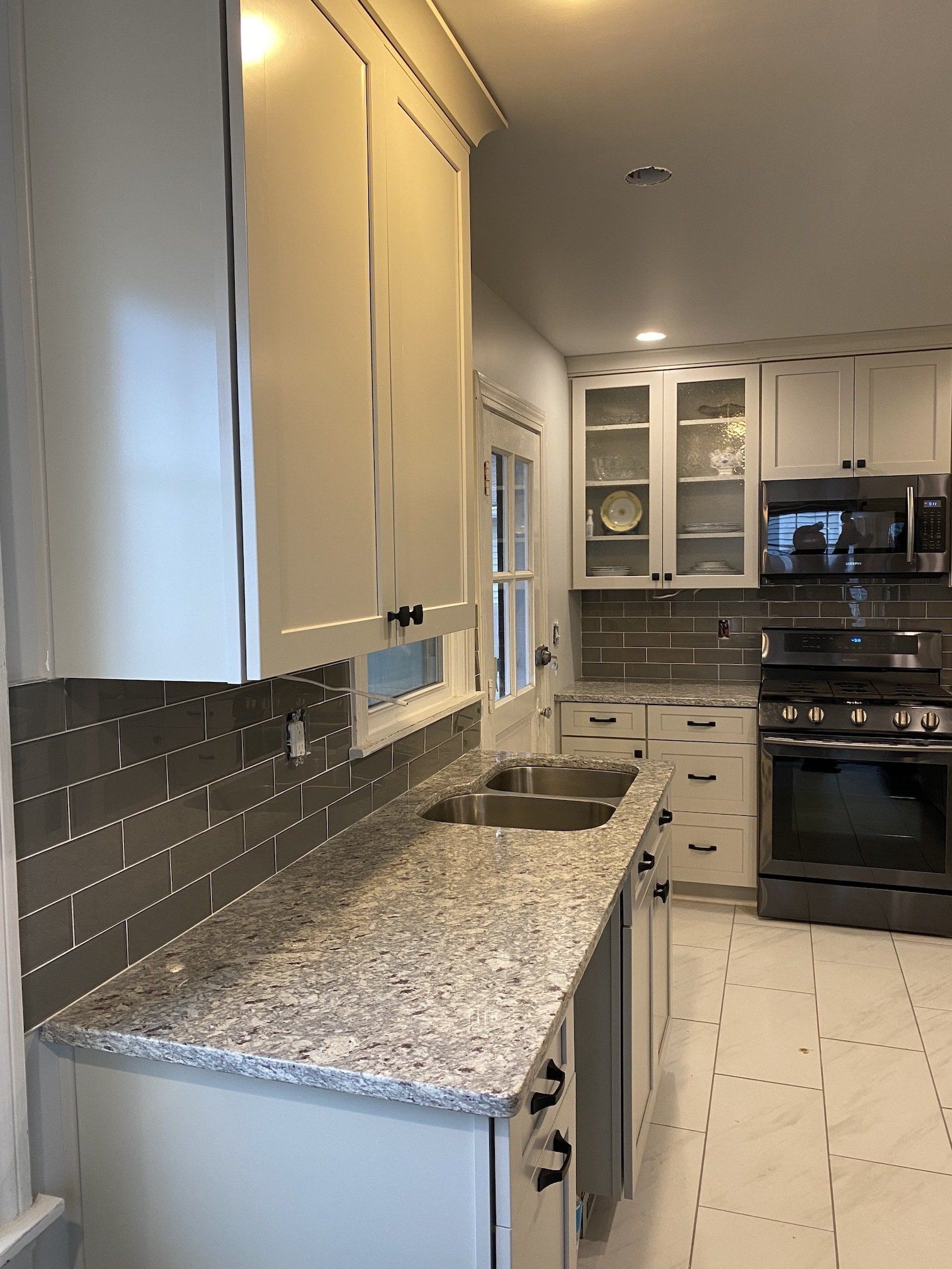 Kitchen with white cabinets, gray backsplash, and granite countertops.