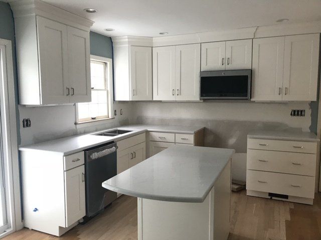 White kitchen with white cabinets, gray countertops, and an island.