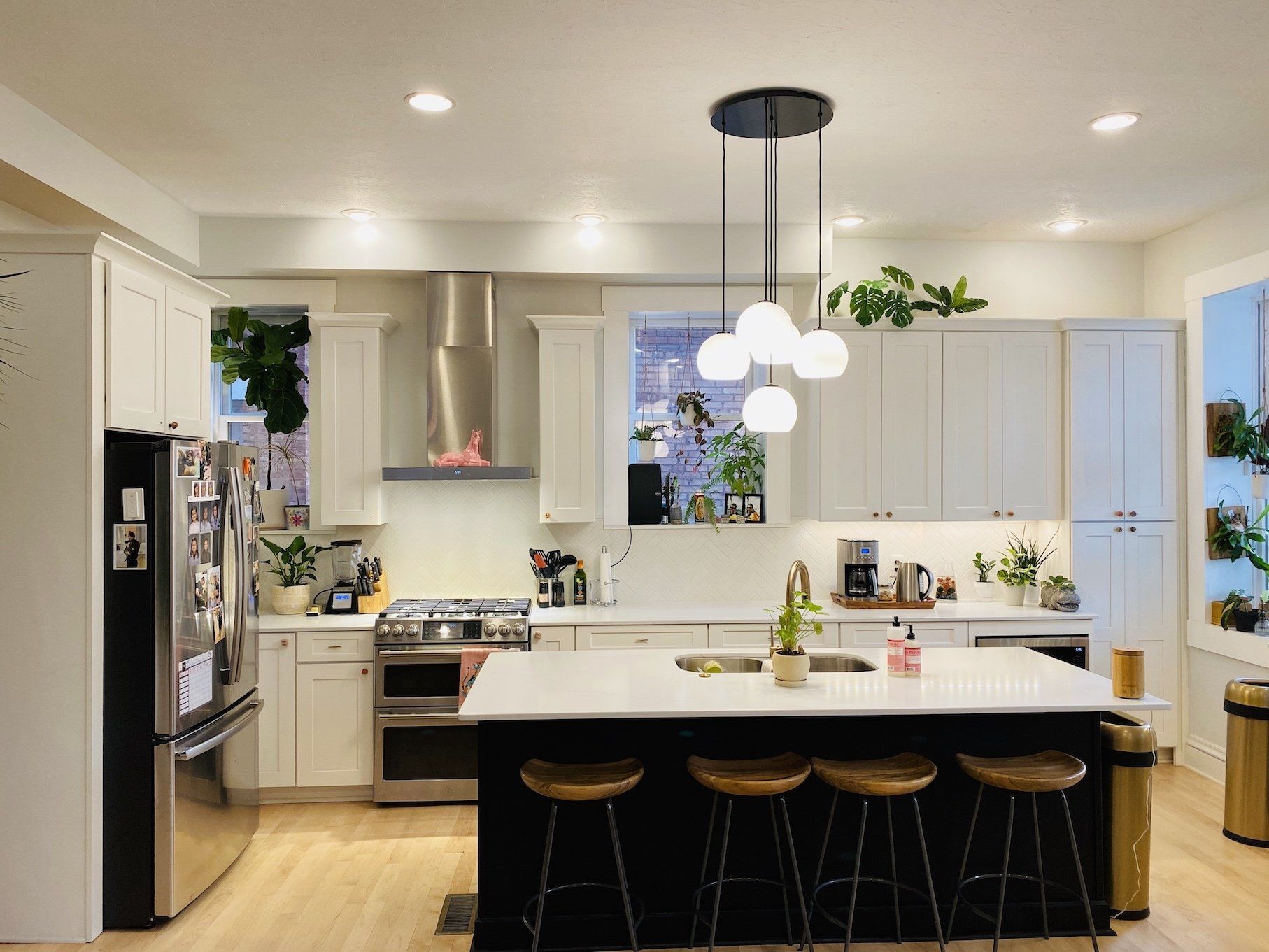 Modern kitchen with white cabinets, stainless steel appliances, and a black island with wooden stools.