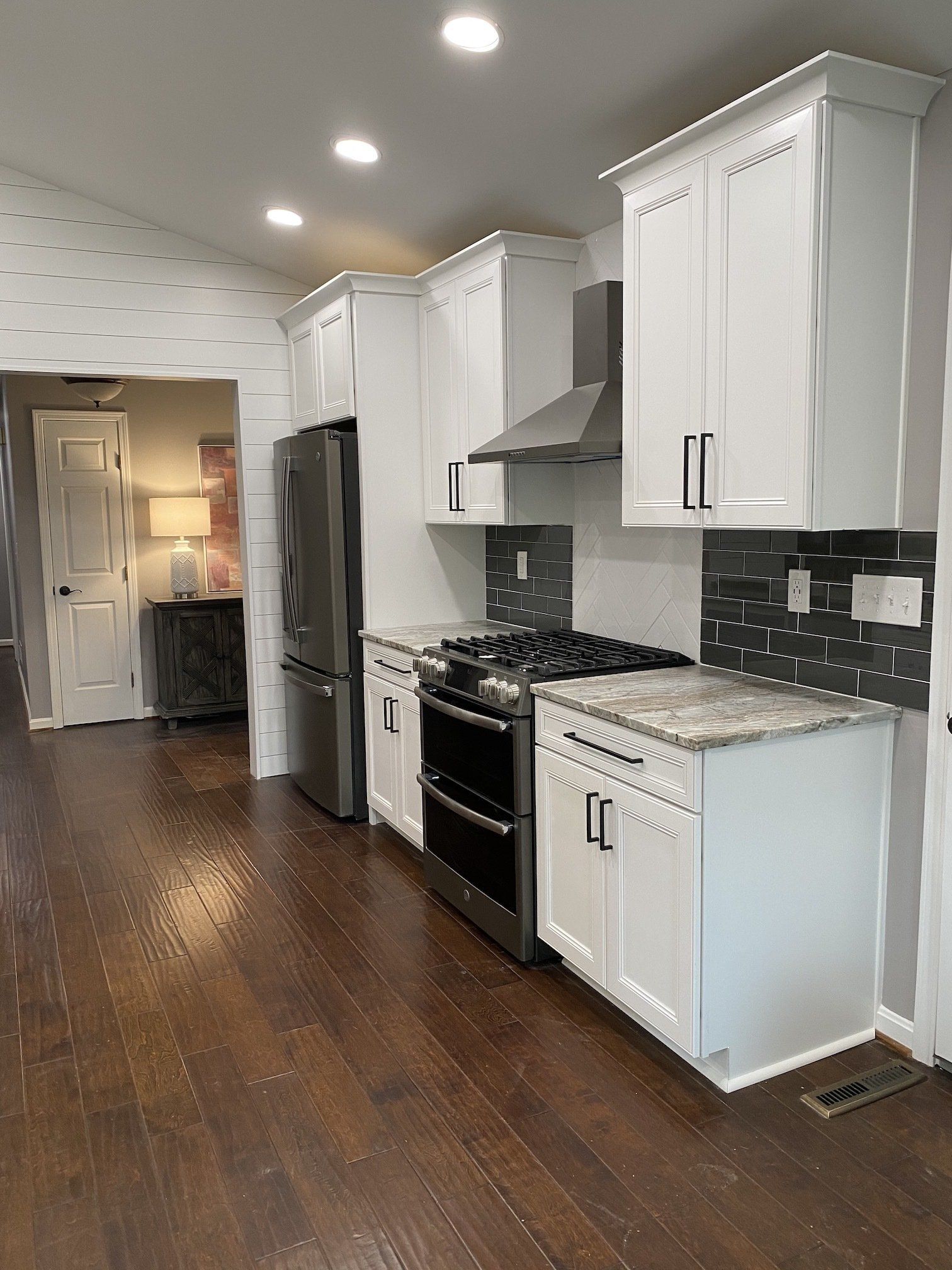 White kitchen cabinets with stainless steel appliances and dark wood floors.