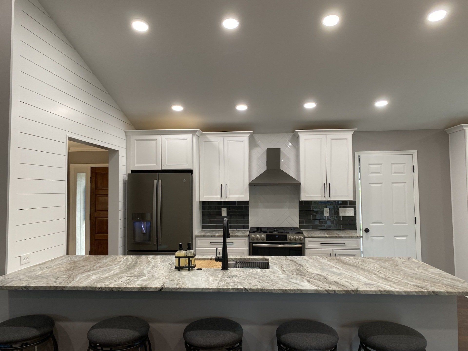 Modern kitchen with white cabinets, stainless steel appliances, and a granite island.