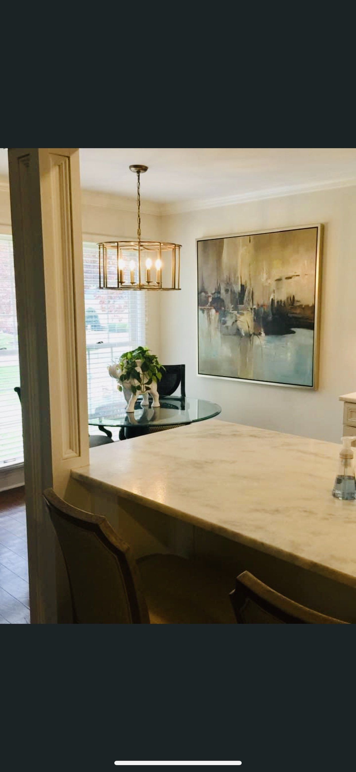 Interior view: dining room with round glass table, art, and a hanging light fixture.