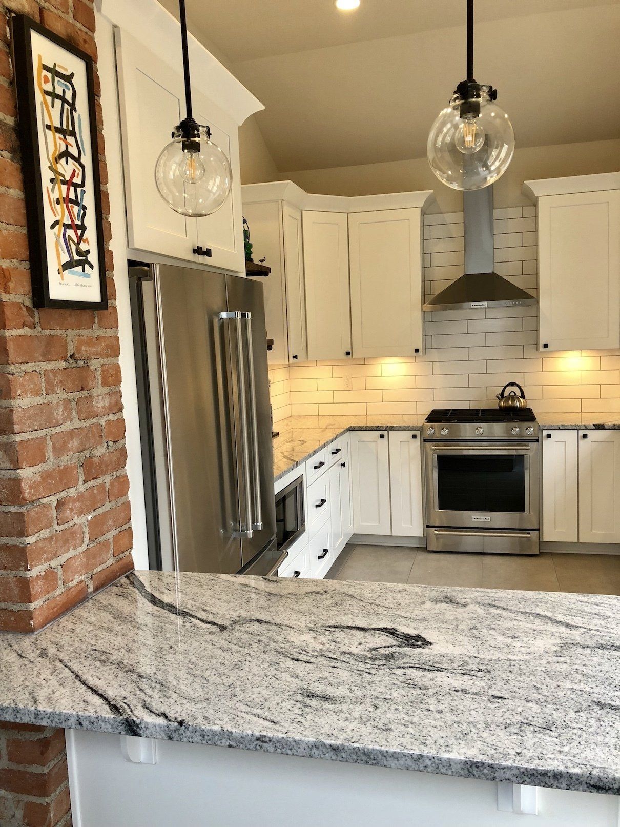 Modern kitchen with white cabinets, stainless steel appliances, and a granite countertop.