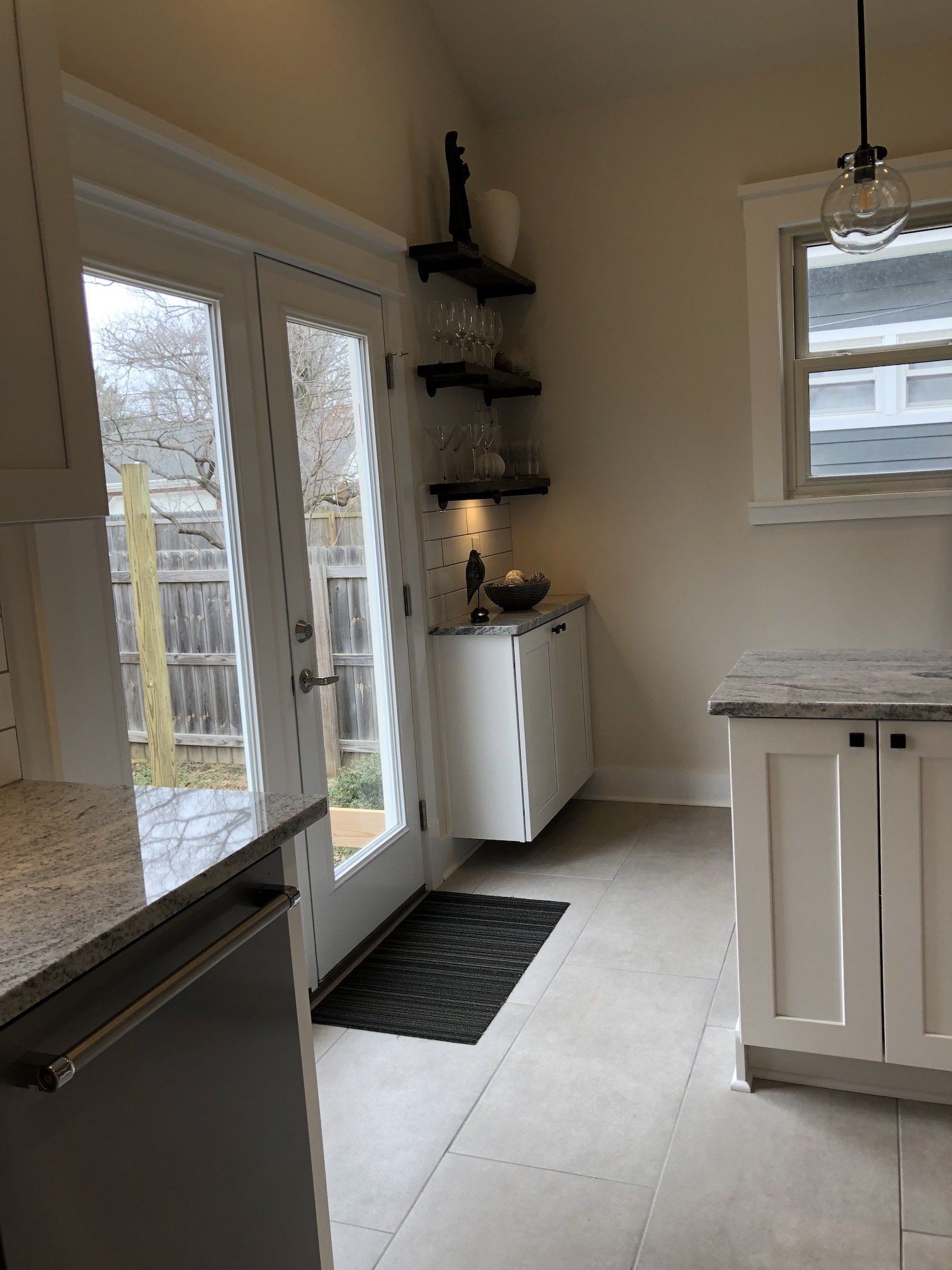 Kitchen with glass doors, white cabinets, and shelves holding glasses.
