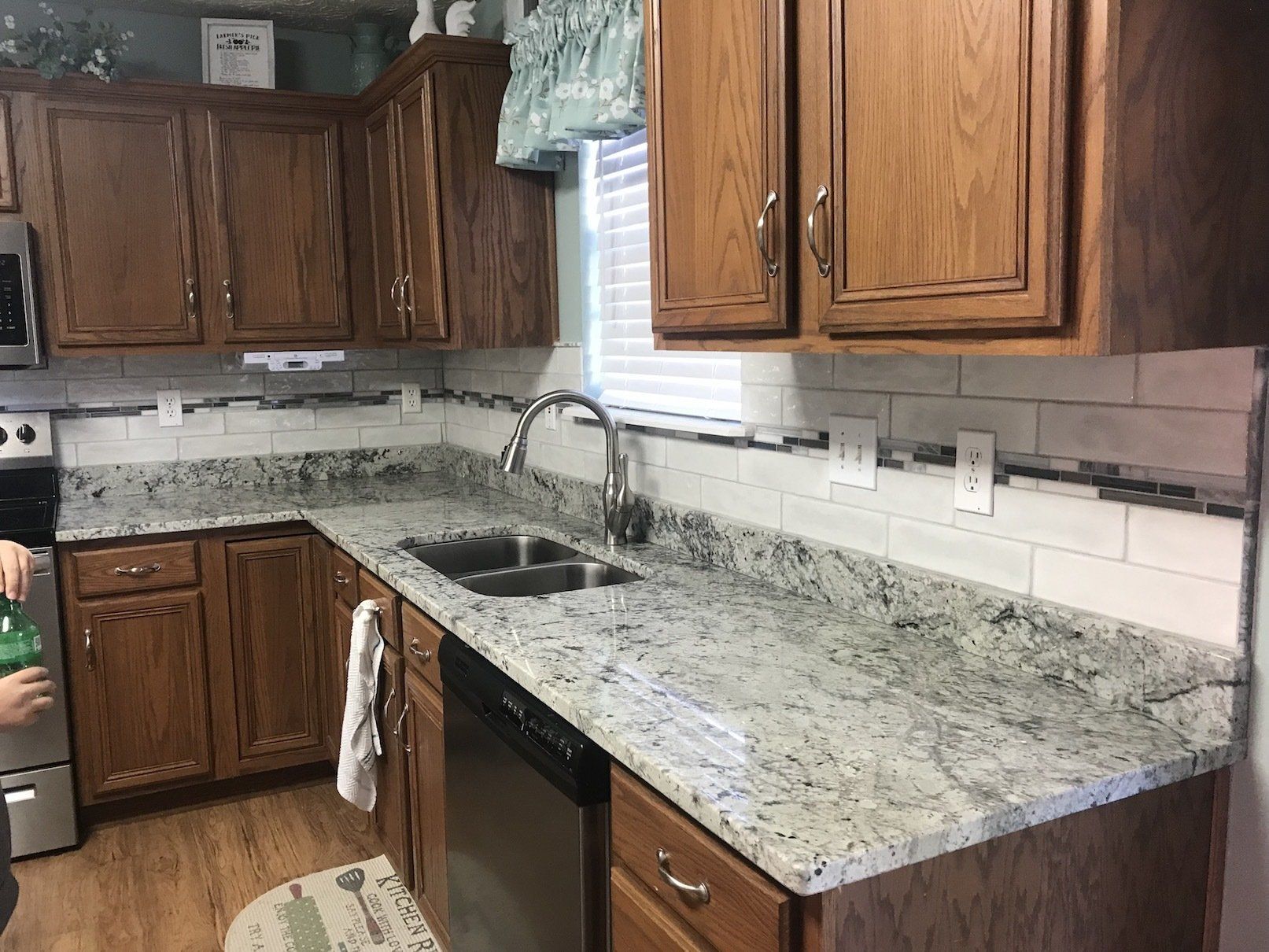 Kitchen with granite countertops, wood cabinets, and white subway tile backsplash. Stainless steel sink and appliances.