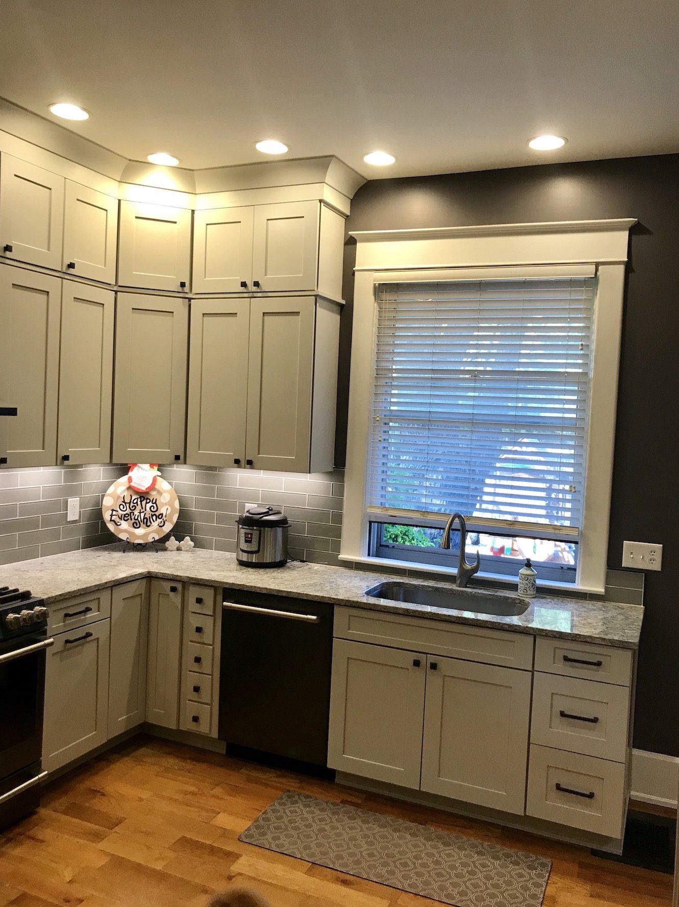 Kitchen with light grey cabinets, stainless steel appliances, and a window with blinds.