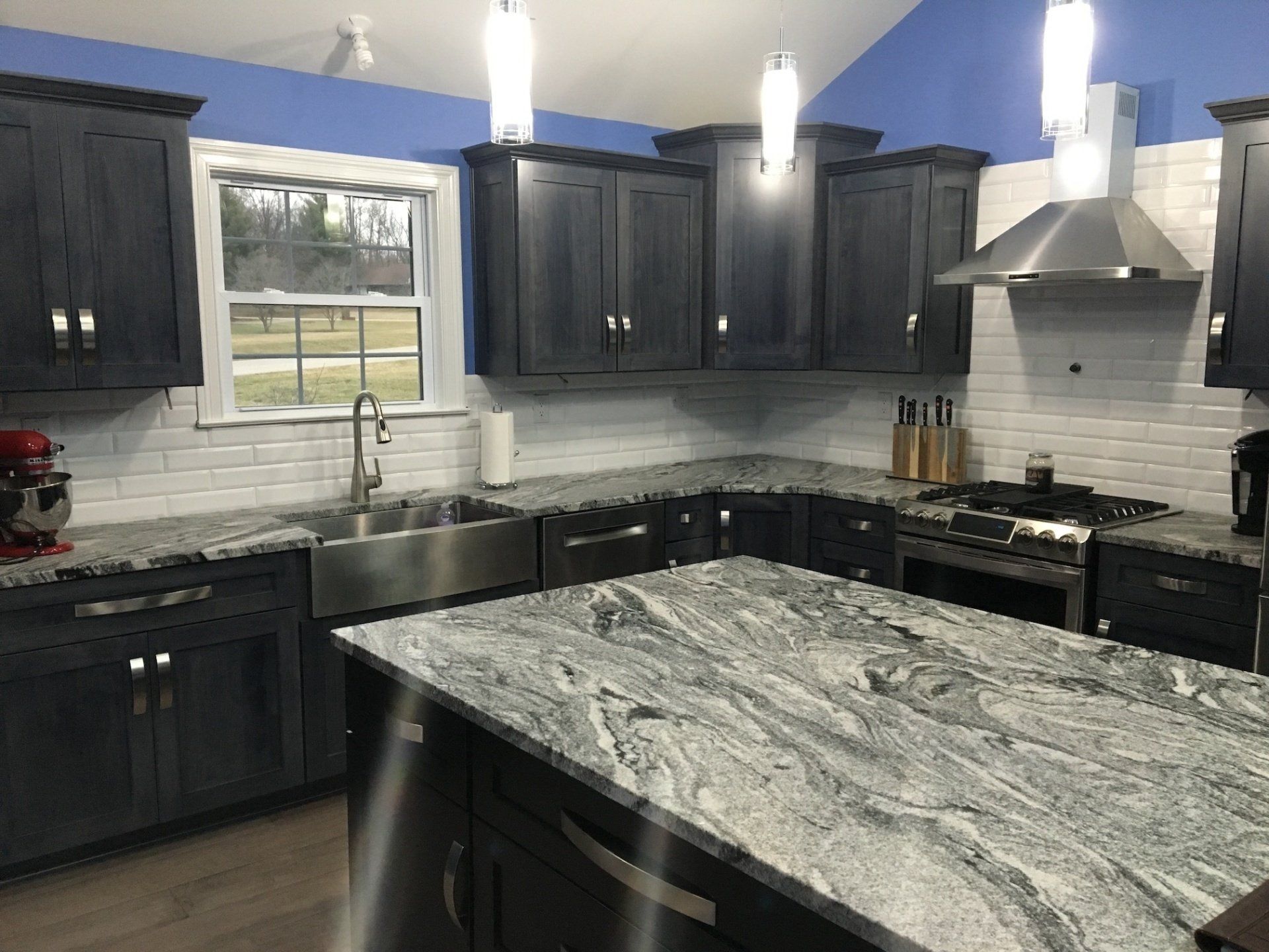 Kitchen with gray cabinets, granite countertops, stainless steel appliances, and blue walls.