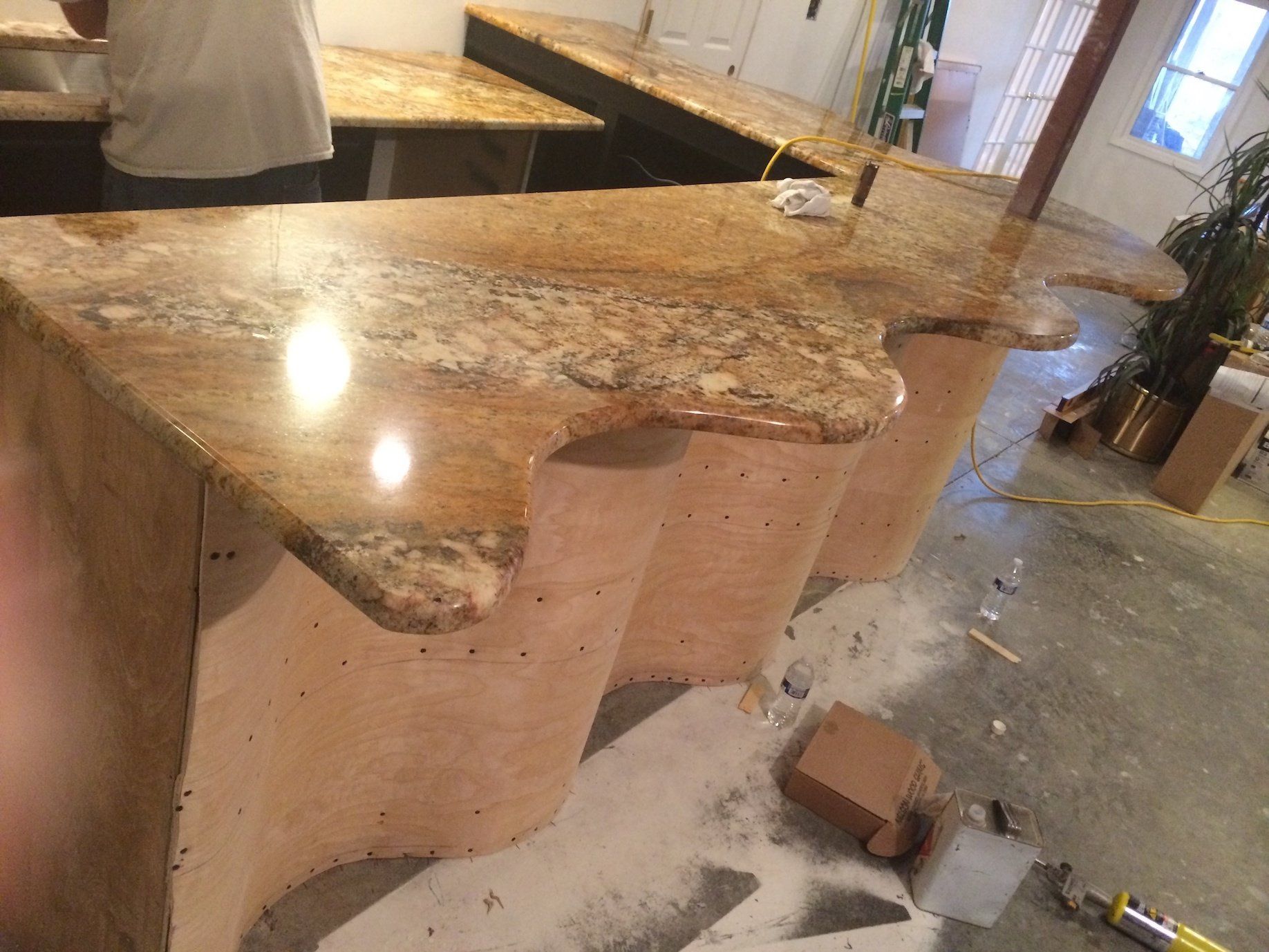 Granite countertop with curved edges on a bar, construction in progress.