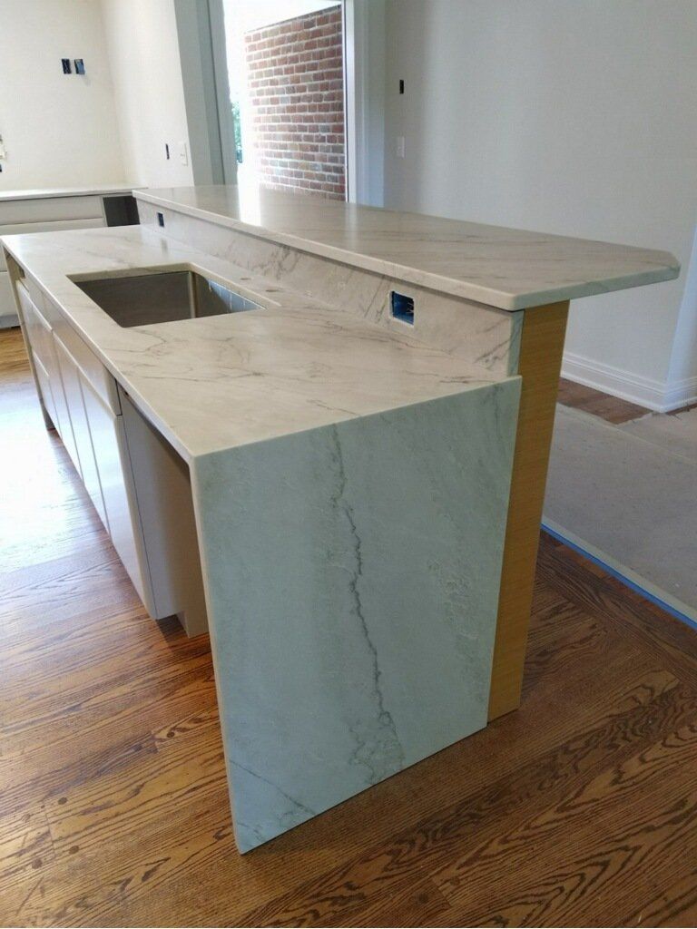 Kitchen island with light-colored countertop and sink, light cabinets, and wood flooring.