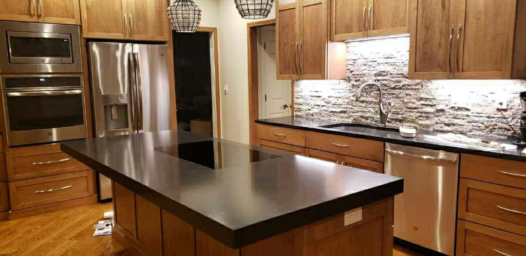 Kitchen with stainless steel appliances, wood cabinets, and a dark countertop island.