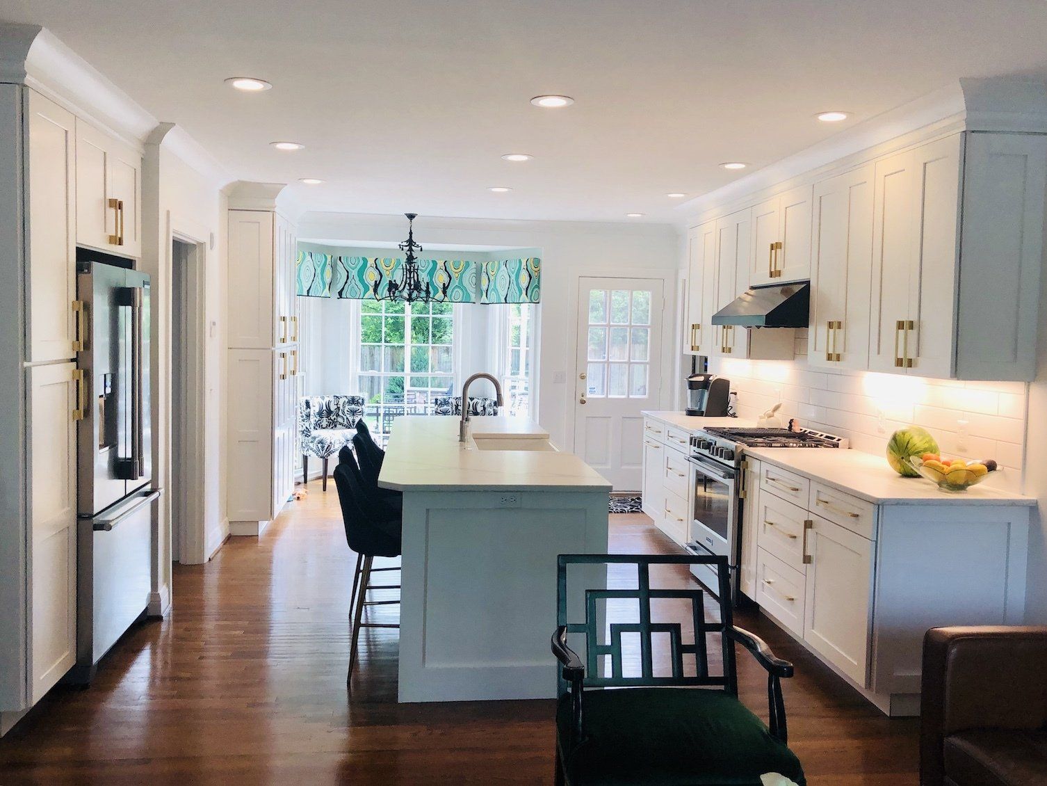 White kitchen with island, cabinets, stainless steel appliances, and dark wooden floors.