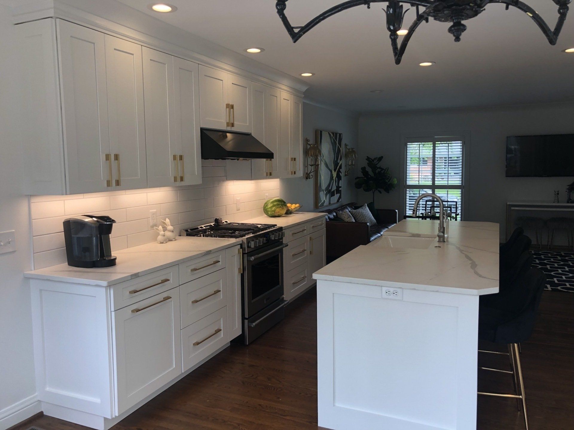 White kitchen with marble countertops, cabinets, stove, and island.