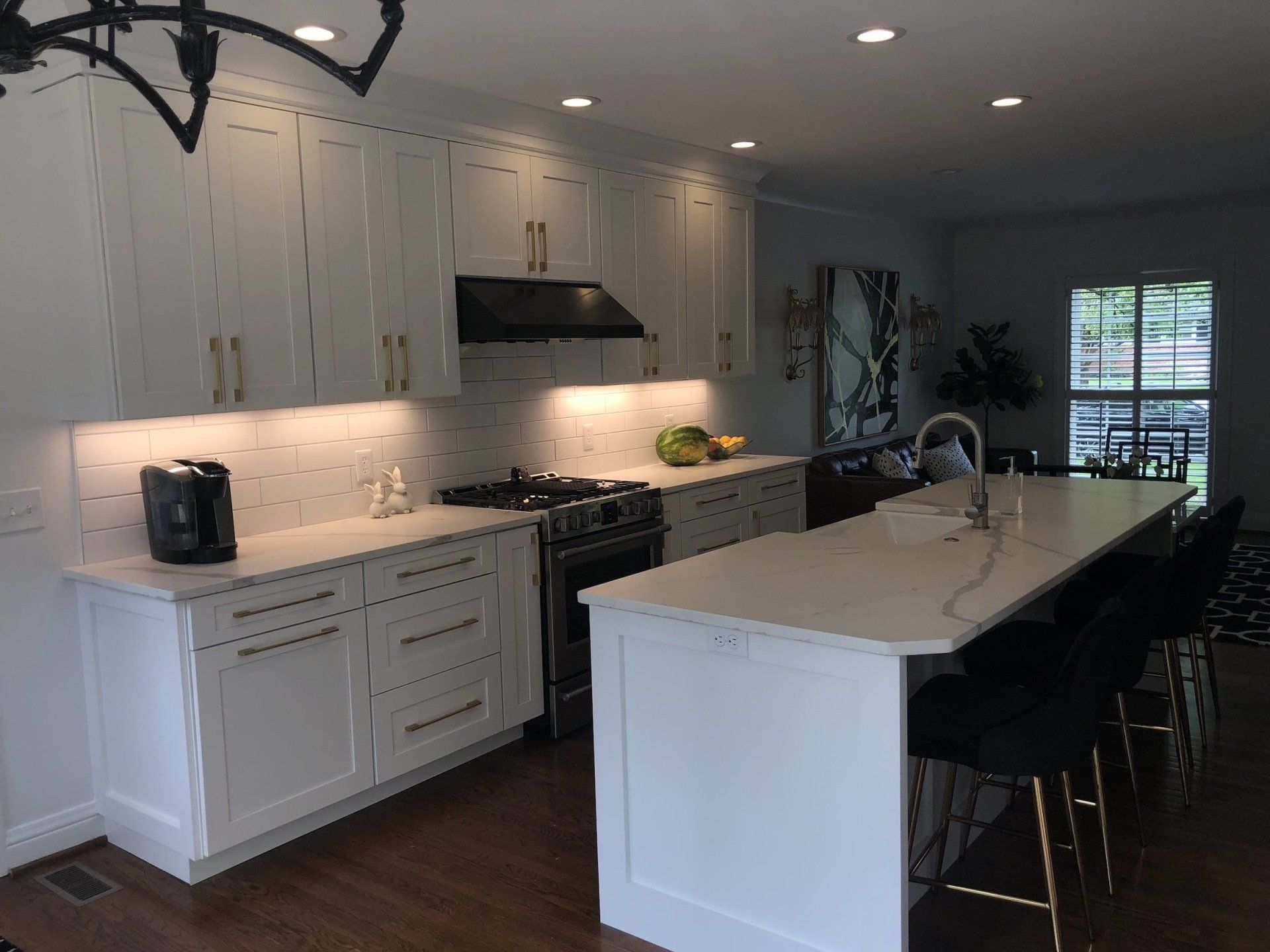 White kitchen with island, cabinets, countertops, and black range hood.