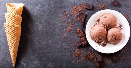 un tavolo nero con sopra coni gelato e una porzione di gelato al cioccolato