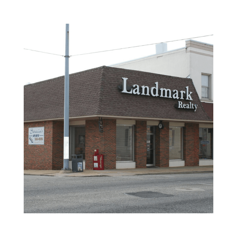 Landmark Realty building, brown brick, with large white sign. Includes a sign for a local business.