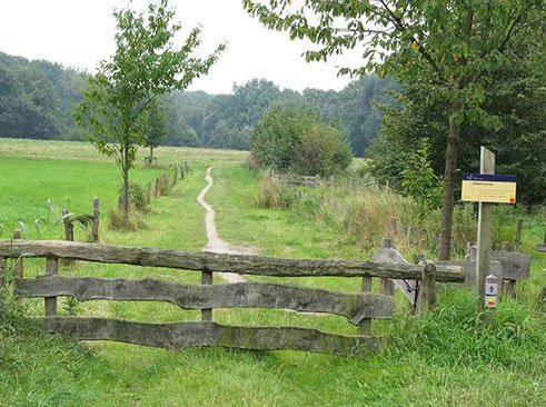 Wandelaars bij houten hek met bergachtig landschap op Outscape.