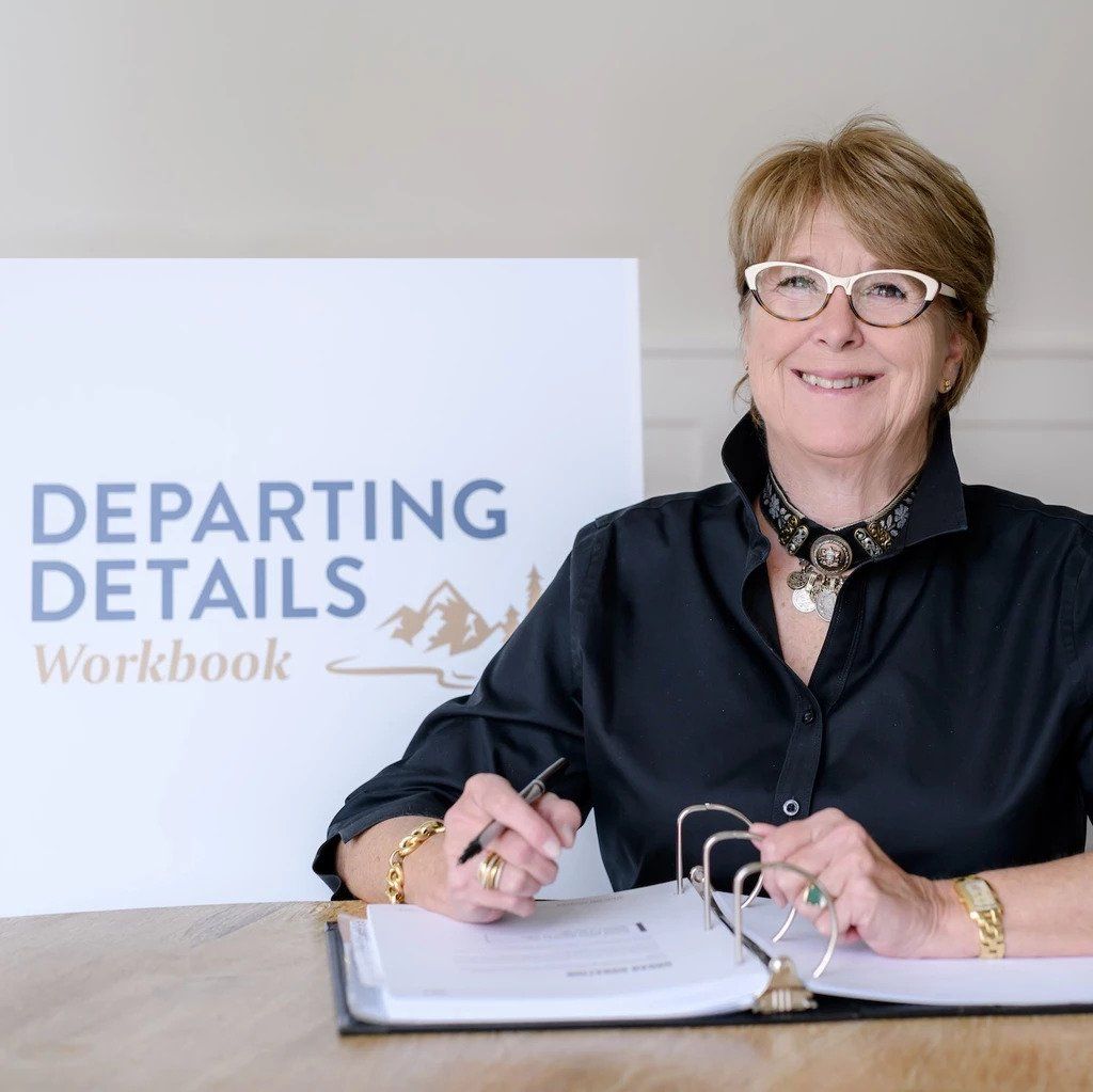 Author, Rosemary Pahl, with a binder in front of her and a Departing Details banner behind her
