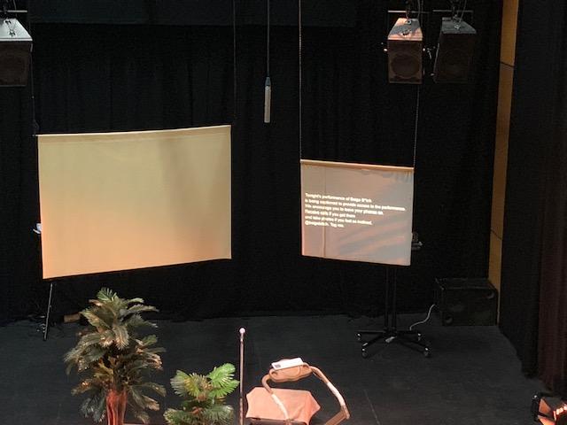 Dark stage with captions displayed on hanging Powerpoint projection. Dark stage with captions displayed on hanging Powerpoint projection.