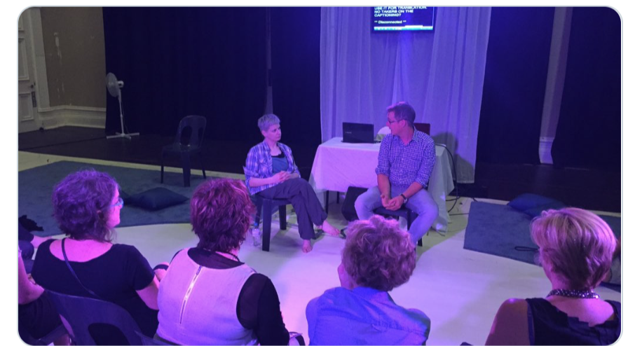 Man & woman people talking in front of audience with captioned screen. Man & woman talking in front of audience with captioned screen.