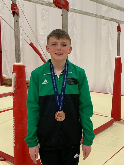 A gymnast wearing a medal and smiling after their competition
