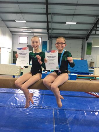Gymnasts sitting on a beam after their competition