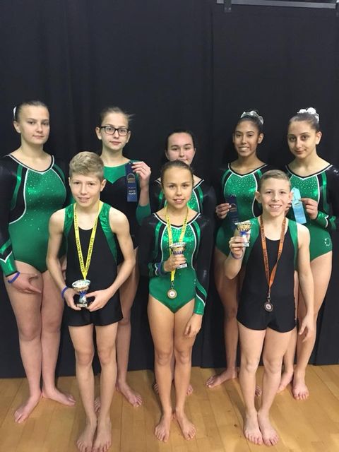 a group of gymnasts at regional finals with medals and trophies