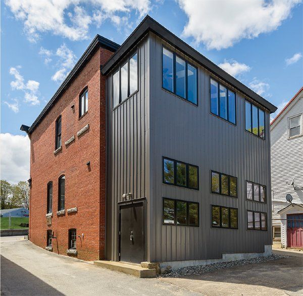 A brick building with a gray siding and lots of windows
