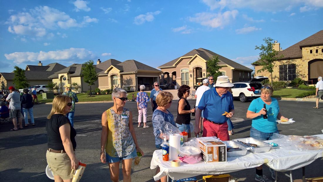 A group of people are standing around a table in a parking lot.