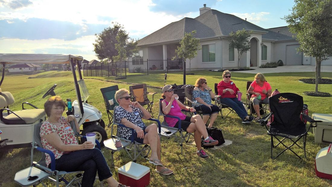 A group of women are sitting in chairs in front of a house.