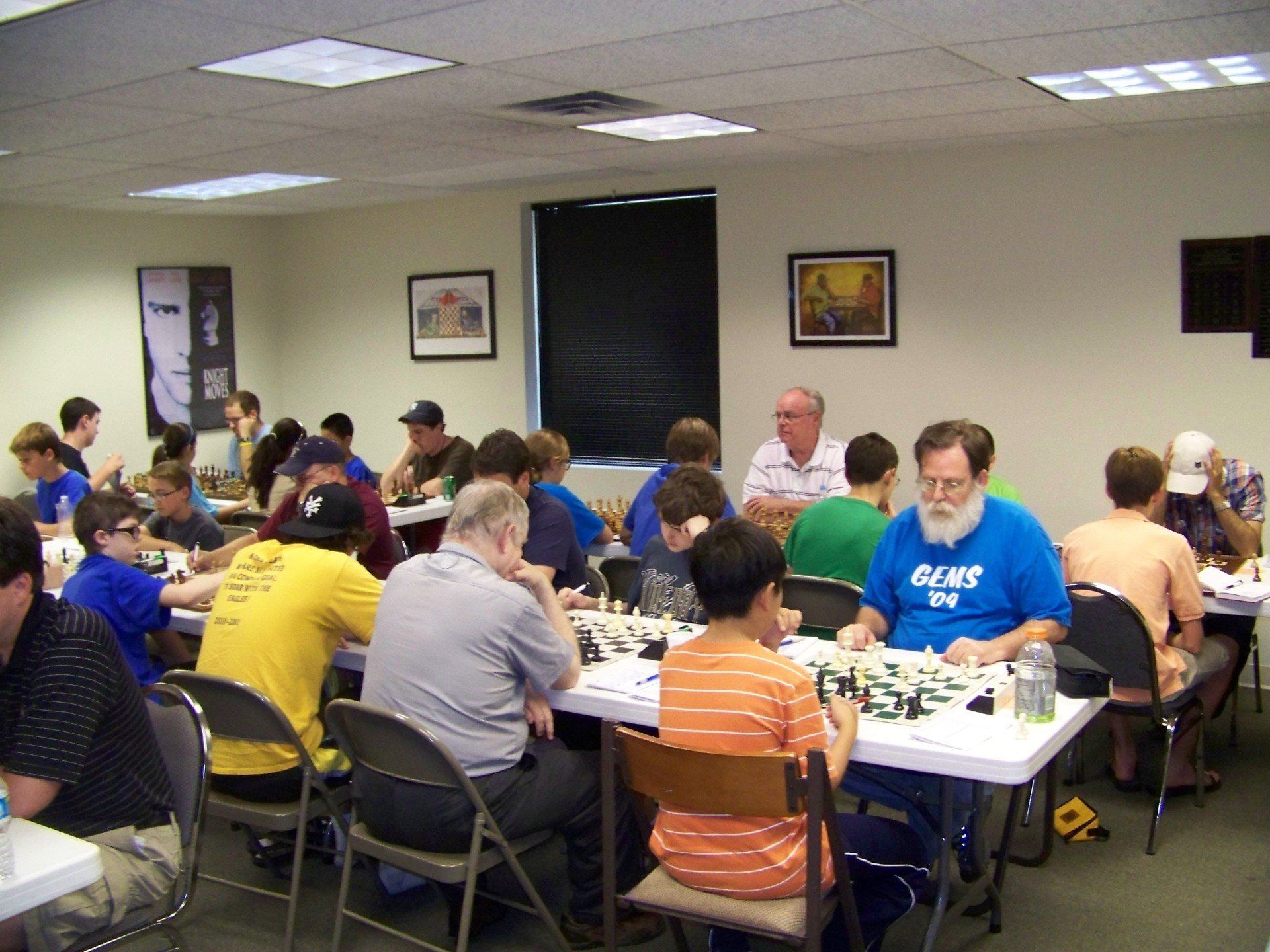 A man in a blue gears shirt sits at a table with other people