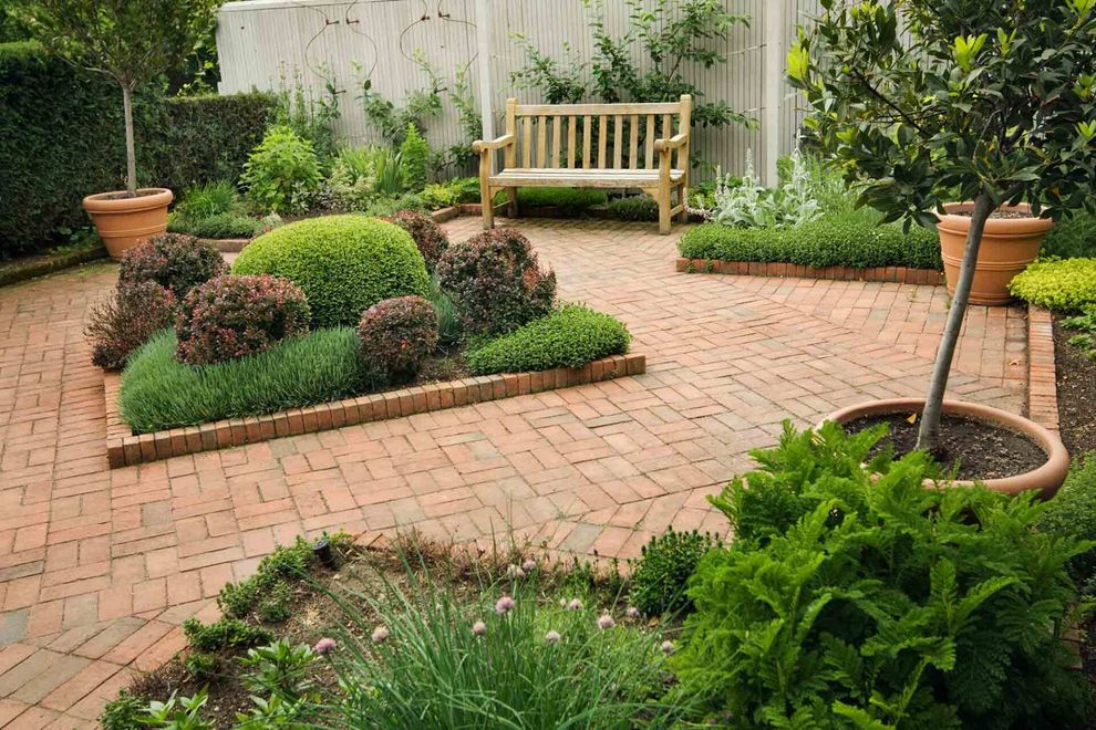 Urban small garden with brick patio, wooden bench and potted plants
