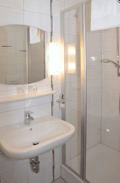 Ein Badezimmer mit Waschbecken, Spiegel und Dusche