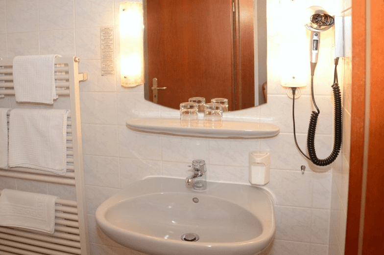 Ein Badezimmer mit Waschbecken, Spiegel und Haartrockner