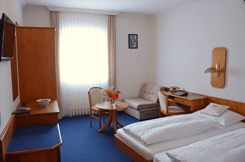 Ein Hotelzimmer mit zwei Betten, einem Schreibtisch und einem Stuhl