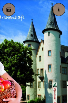 Eine Person, die einen Korb mit Äpfeln vor einem Schloss hält