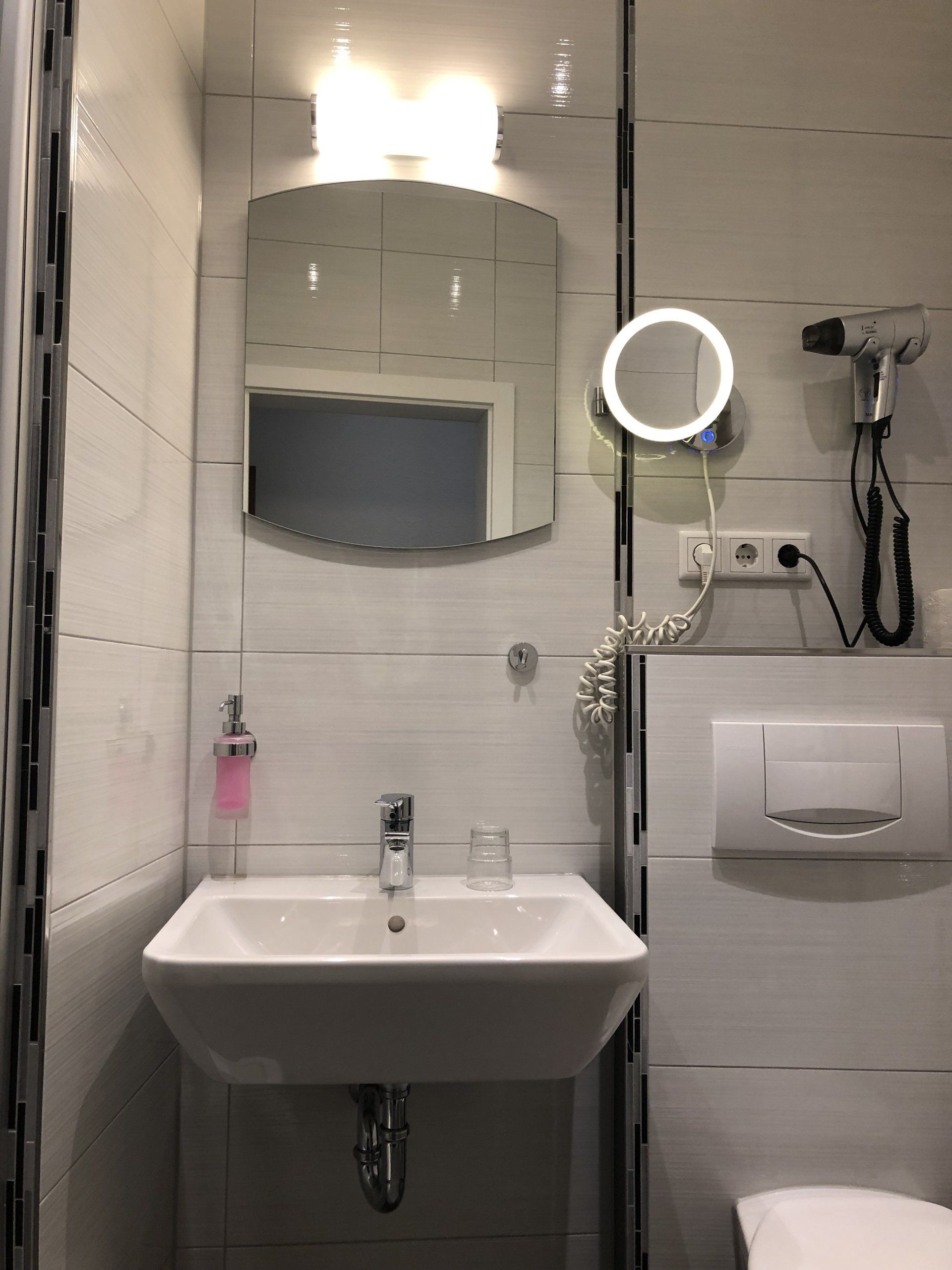 Ein Badezimmer mit Waschbecken, Spiegel und Haartrockner