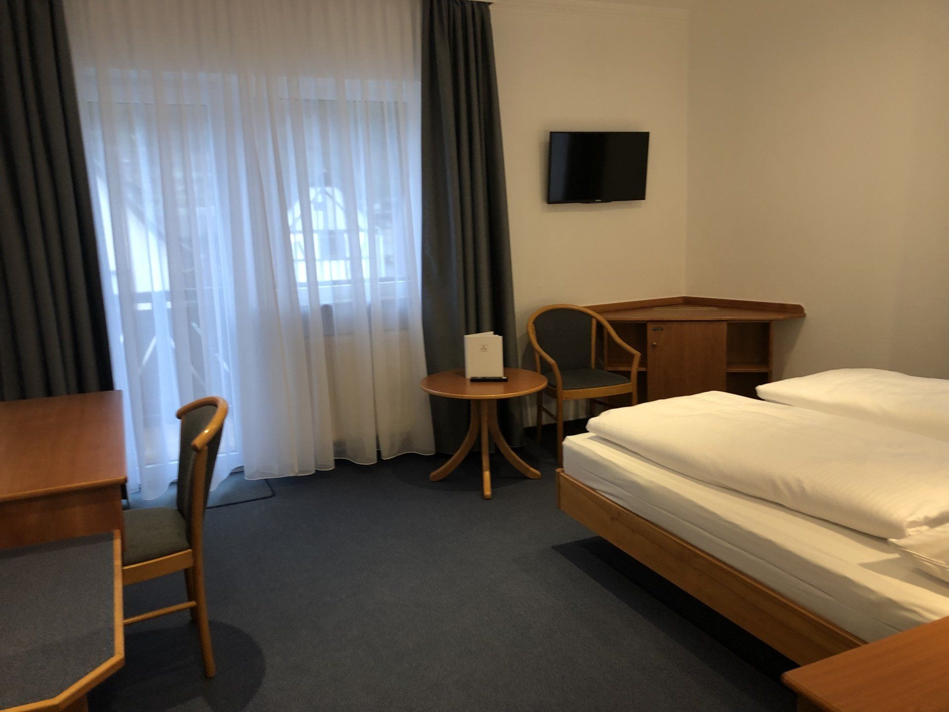 Ein Hotelzimmer mit Bett, Schreibtisch, Stuhl und Fernseher