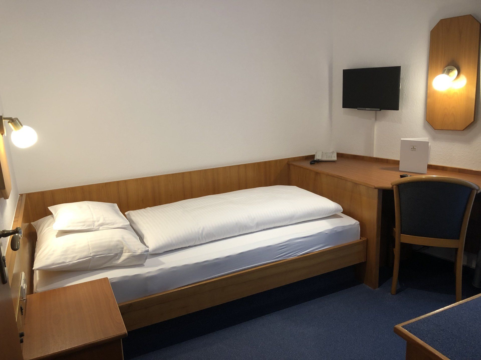 Ein Hotelzimmer mit einem Einzelbett und einem Schreibtisch
