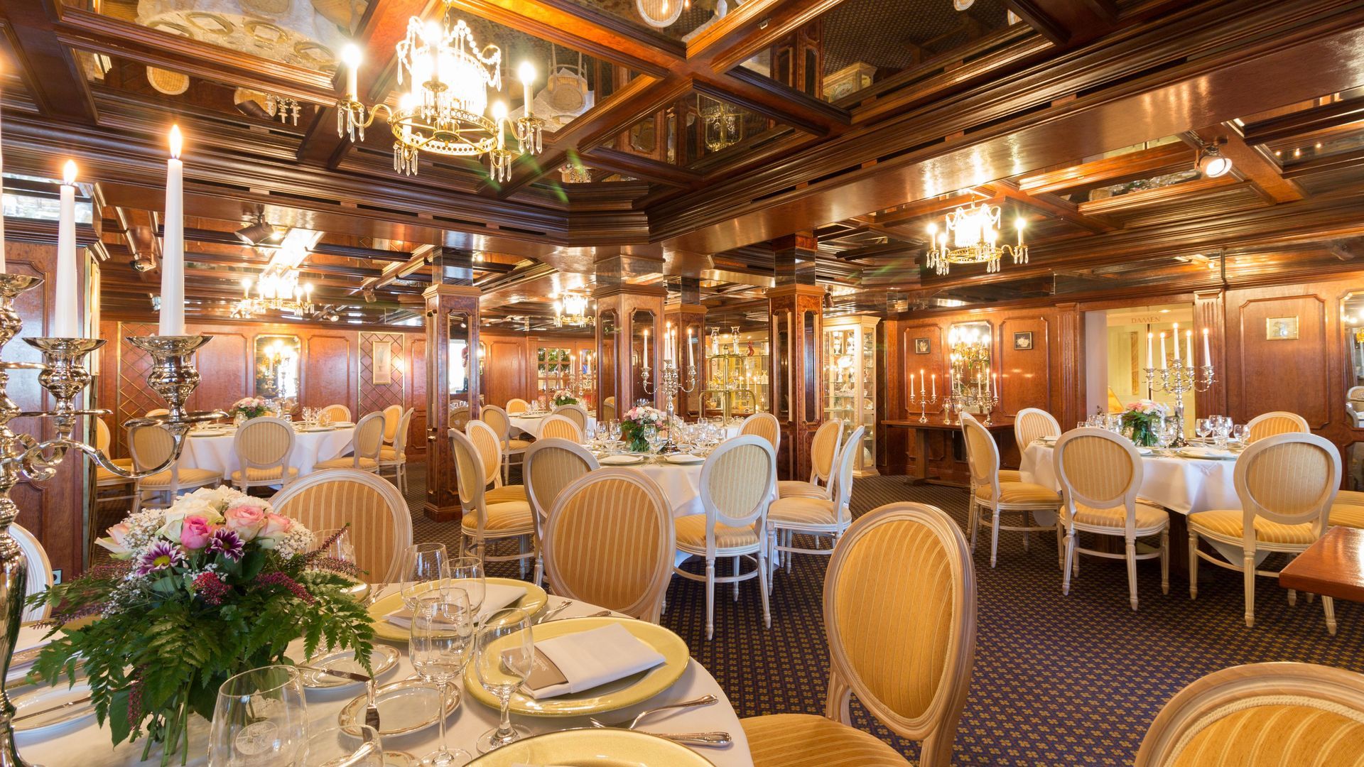 A large dining room filled with tables and chairs and candles.