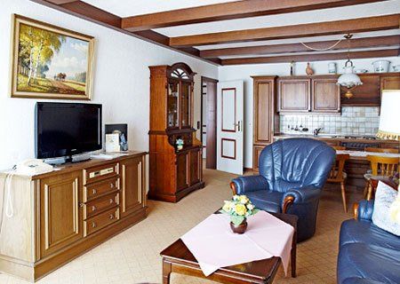 A living room with a couch , chair , table and television.