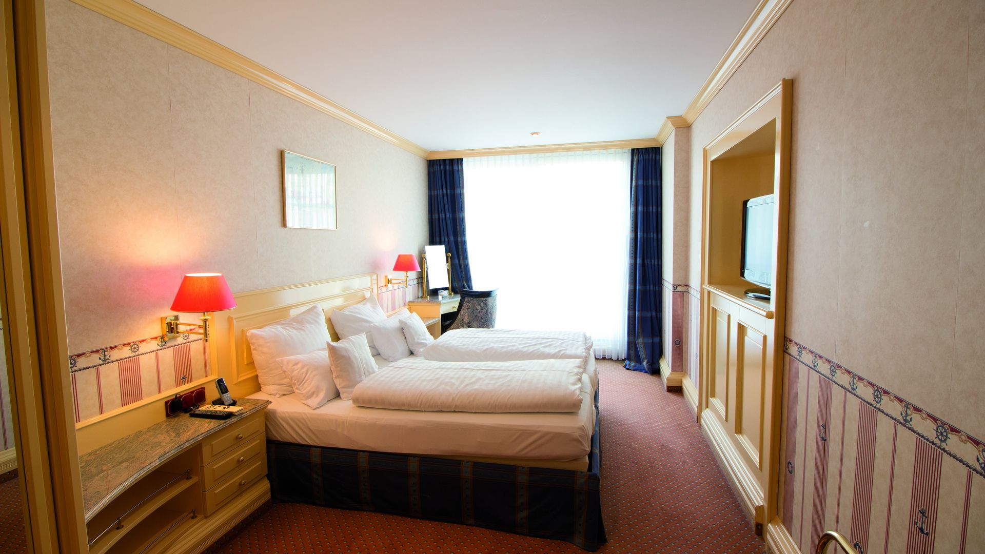 A hotel room with two beds , a desk and a television.