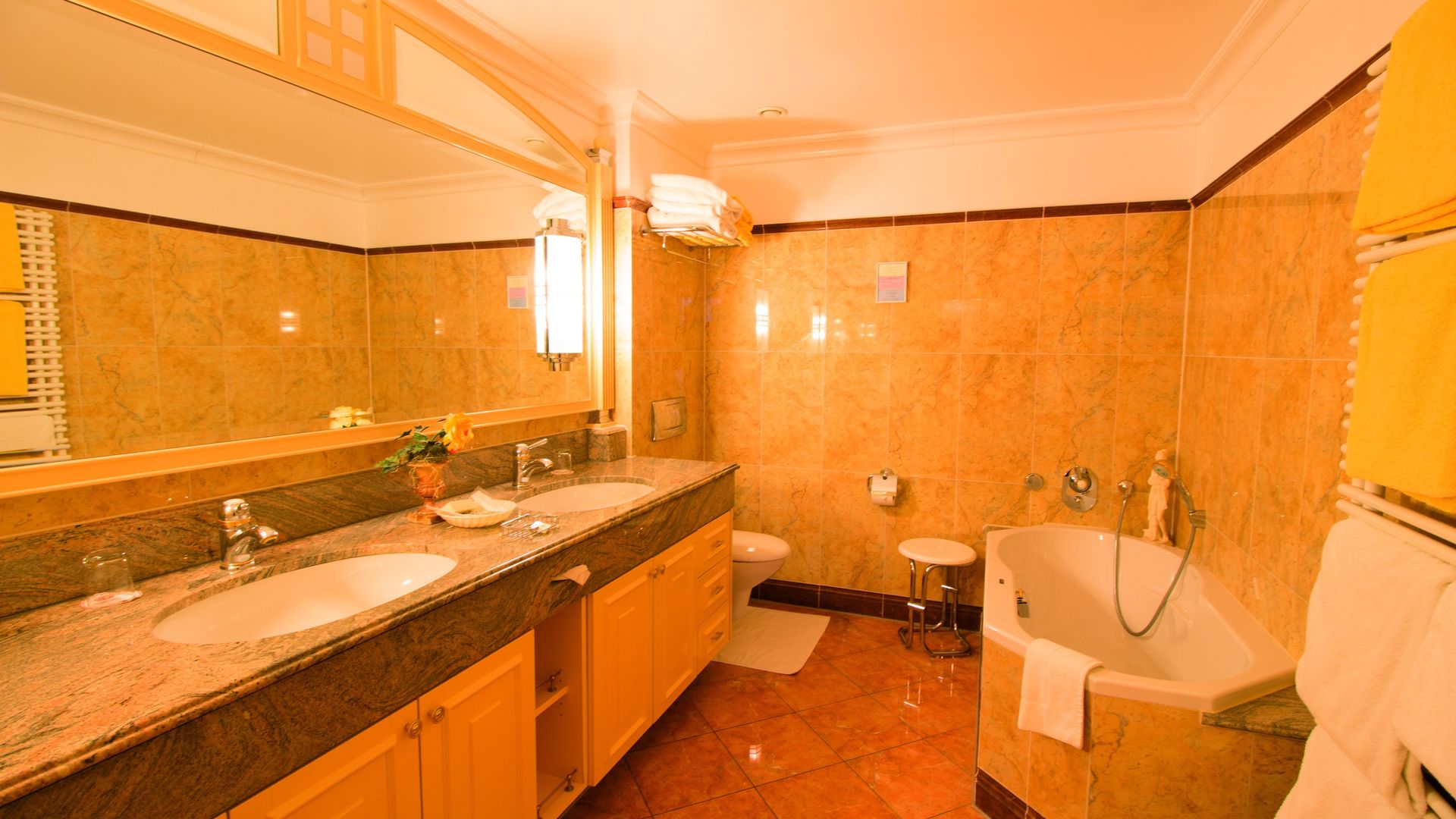 A bathroom with two sinks , a tub , a toilet and a mirror.