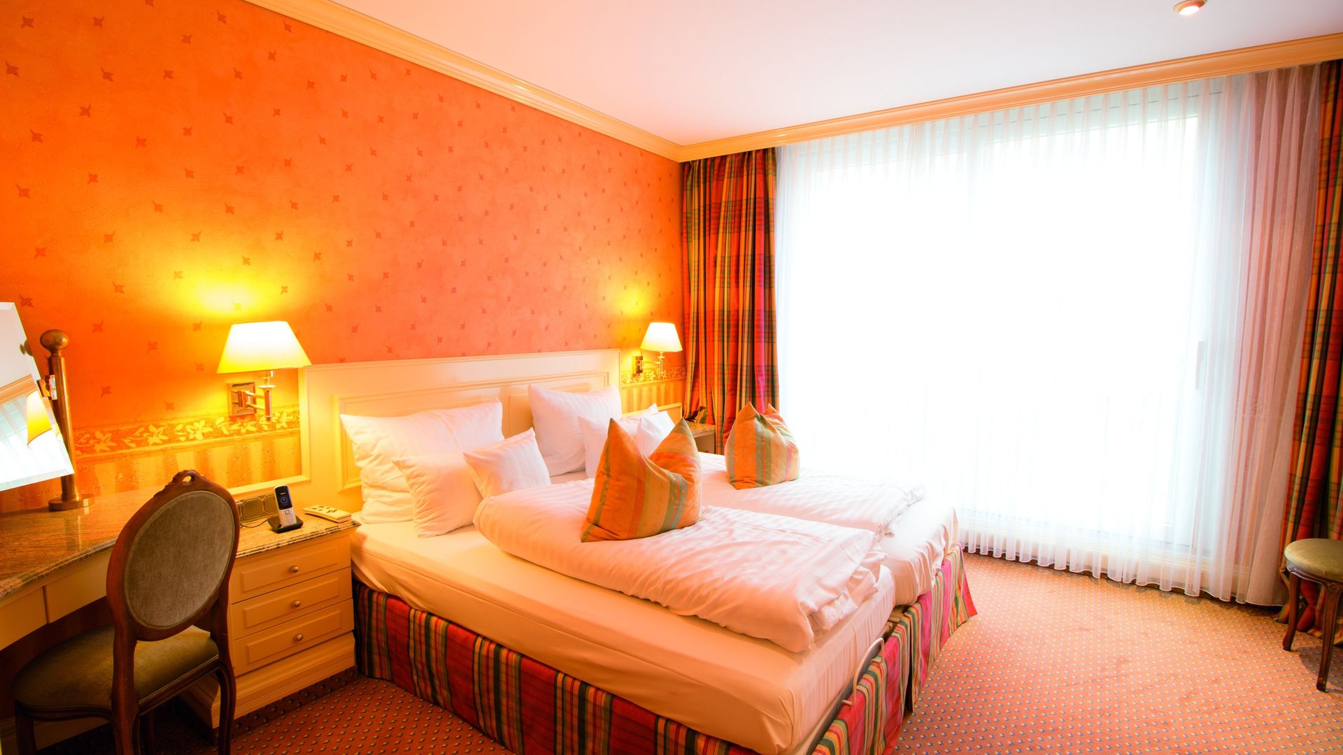 A hotel room with two beds , a desk and a window.