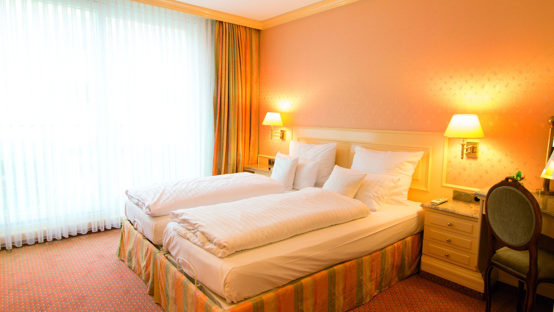 A hotel room with two beds and a desk.